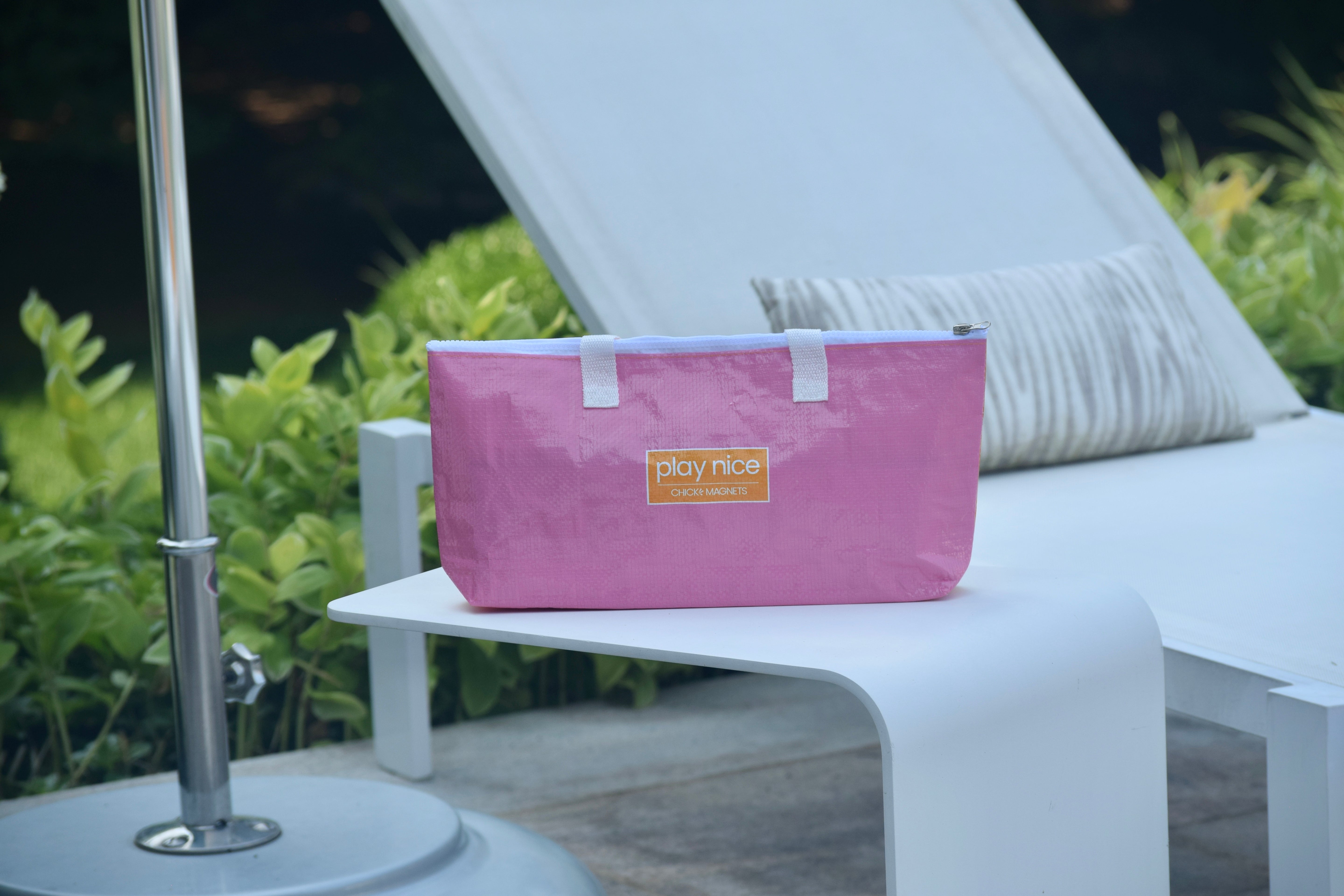 "play nice" pink & orange carryall shown in a pool setting.